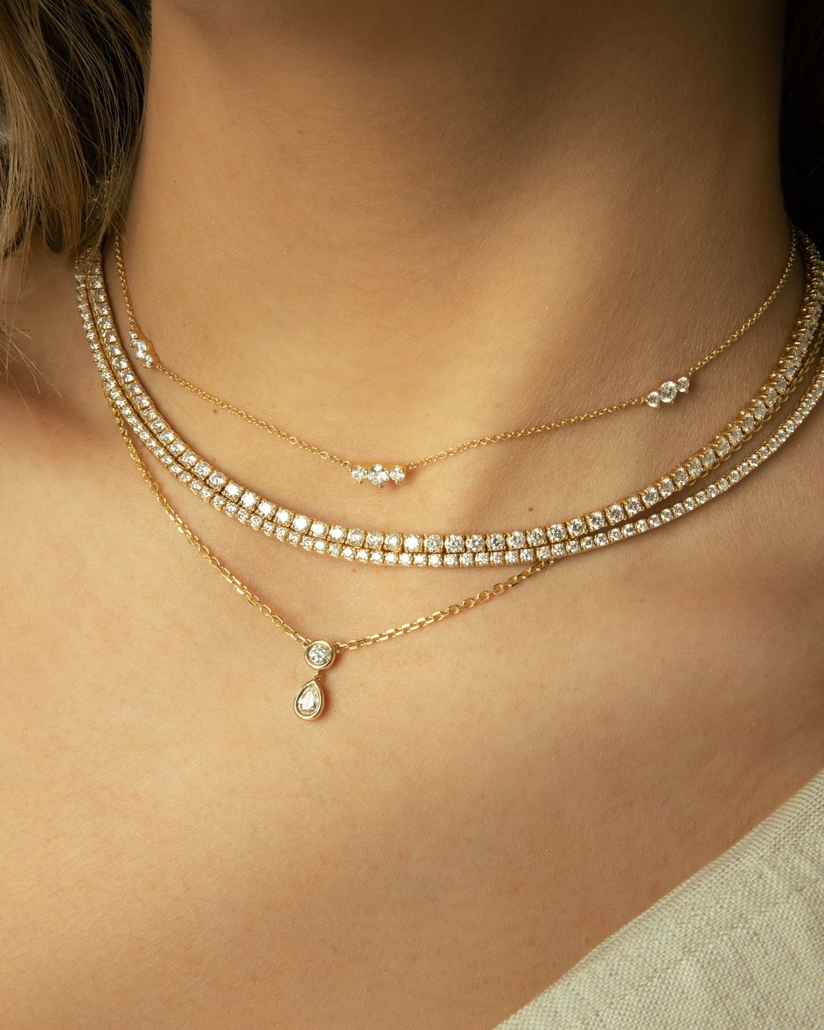 Close-up of a person wearing multiple gold necklaces with small pendants 